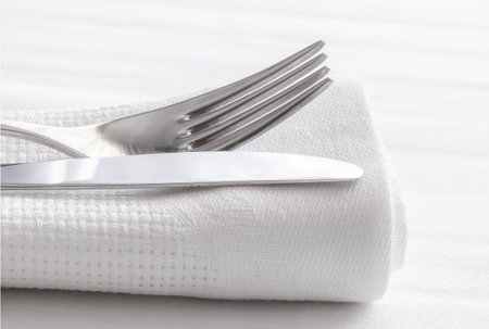 Silver fork and knife with napkin on white table cloth. Restaurant dining concept backgroundの写真素材