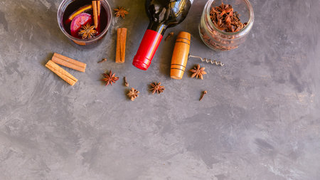 Mulled wine drink, red wine bottle and different spices on gray concrete background. Perfect winter beverage for cold days. top viewの写真素材
