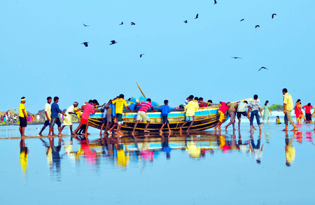 The fisher men in Vizag pushing the boat in to sea for fishing.のeditorial素材