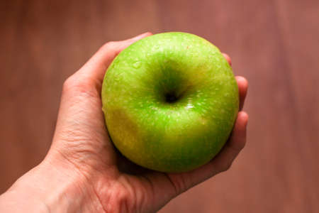 Green apple with drops of water in handの写真素材