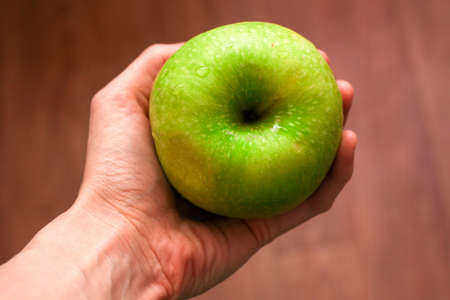 Green apple with drops of water in handの写真素材