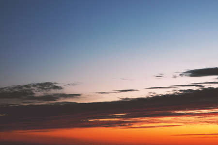 Bright orange sunset with dark clouds and blue skyの写真素材