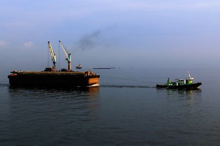 a small tugboat pulling a barge loadedの写真素材