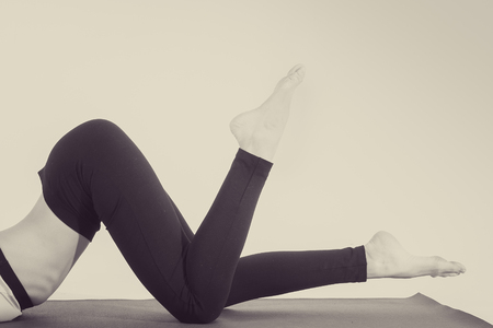 Beautiful young girl in top and pants for yoga near white wallの写真素材