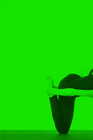 Young girl doing a yoga pose in green colorの写真素材