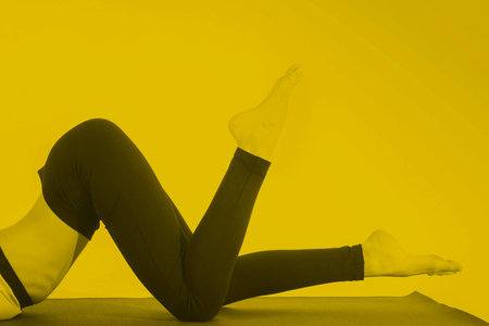 Young girl doing a yoga pose in yellow colorの写真素材