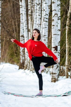 Yoga in the snow. Girl practicing yoga in the Park. Time of year winter. Snow-covered trees.の写真素材