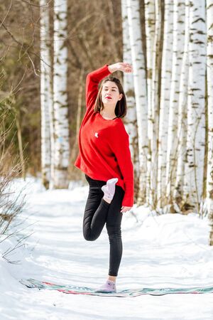 Yoga in the snow. Girl practicing yoga in the Park. Time of year winter. Snow-covered trees.の写真素材
