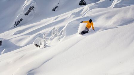 Snowboarder going down a mountain trail snowの写真素材