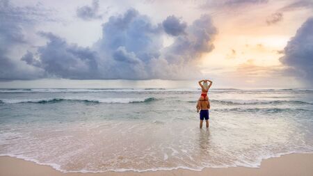 Girl sitting on the shoulders of the guy on the ocean sun cloudsの写真素材