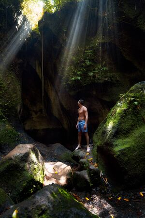 The guy in the canyon the sun's rays beat into the crevice waterfall Tukad Cepung