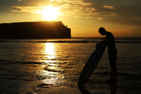 Surfer at sunset by the sea. Sports, travel, sunset.