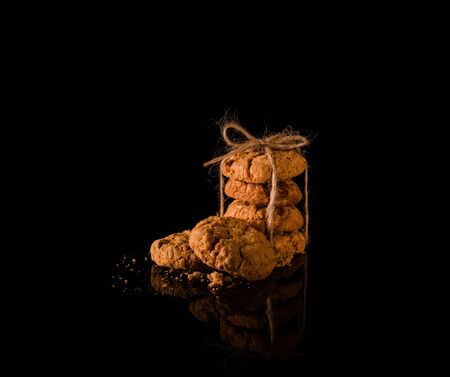 homemade cookies tied with a rope on a black background with a reflection