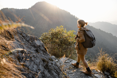 Young girl with backpack walking on the mountains path in the sunlightの写真素材