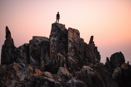 Man stands on the peak of rock and watching to sundown. Beautiful moment the miracle of nature.の写真素材