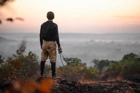 Travel photographer taking a shots at sunrise. Hipster with a little camera in the good lightの写真素材