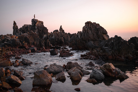 Man stands on the peak of rock and watching to sundown. Beautiful moment the miracle of nature.の写真素材