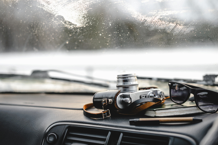 Notebook, glasses and film camera on the dashboard in the car. Closeup shotの写真素材