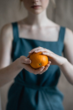 Hands holds orange. Vertical shotの写真素材