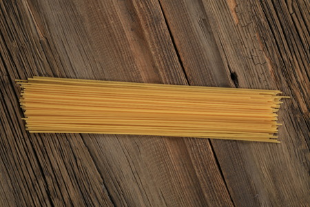 Spaghetti lies on a wooden table. Table made of old wood.の写真素材