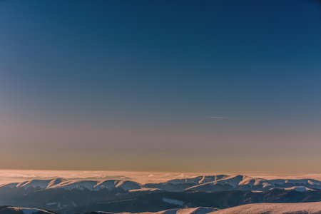 Beautiful winter landscape with snow covered mountains and blue sky at sunset