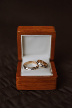 Close-Up Of Wedding Rings In Box On Table. wedding rings Two golden wedding rings in a wooden box on a soft pillow.の写真素材