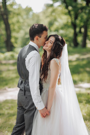 Stylish young brides, happy on their day, enjoy each other. Holding hands in a spring park. Portrait. Spring wedding. Natural makeupの写真素材