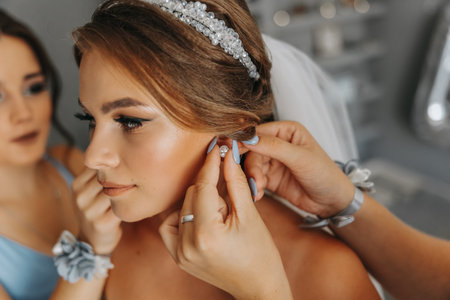 The bride's friend helps in the morning, fastens earrings with a boutonniere on her hand, the bride...
