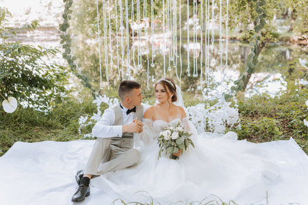 Groom and bride on their wedding day sitting holding hands outdoors.の写真素材