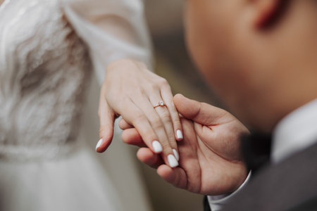Stylish young brides, happy on their day, enjoy each other. The groom puts on the bride's wedding ring. Close-up photo. Spring wedding.の写真素材