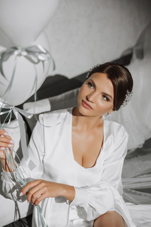 Hairstyle with an elegant wedding hair accessory. The bride holds gel balls in her hands. Gentle and stylish makeupの写真素材