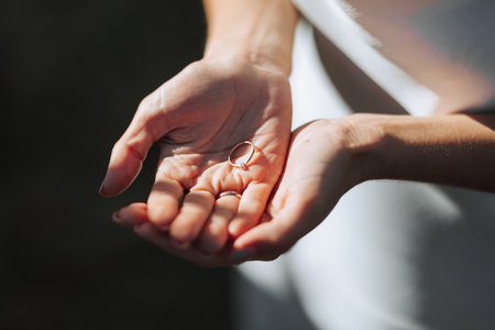 Close-up of an elegant diamond ring on the hand of a woman in a white dress and sun shades. love and wedding concept. soft and selective focus.の写真素材
