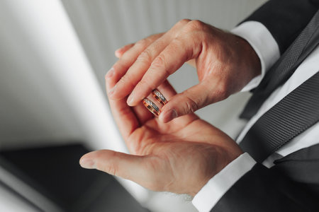 On a man's palm there are two wedding rings. The groom holds the rings. Wedding tradition. Gold...