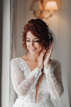 Red-haired bride in a beautiful dress, model posing, portrait photo, net dress. Wedding. wedding bouquet Morning of the bride. A happy bride is waiting for the groom.の写真素材