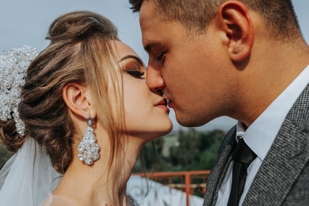 the bride and groom against the background of the sky. Royal wedding concept. The groom kisses the...