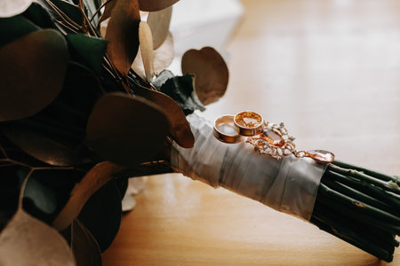Accessories for the groom's wedding. Luxurious bouquet of the groom. Golden wedding invitation, golden rings, cufflinks on wooden floor background. Men's fashionの写真素材