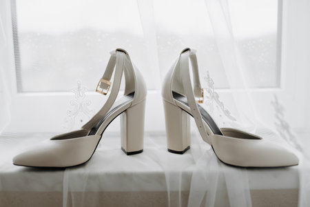 White elegant shoes. A pair of classic white shoes standing on a window sill on a white background. Fashion. Style. Wedding photoの写真素材
