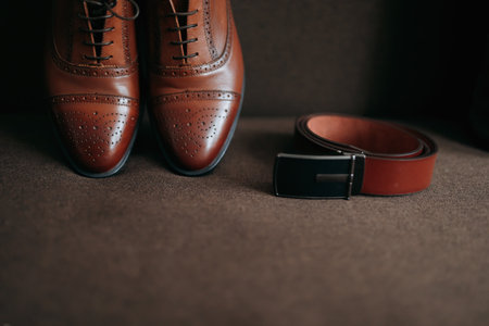 Men's shoes and belt. Elegant red men's leather shoes and belt on a brown background. Men's style. Fashion. Businessの写真素材