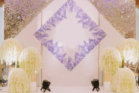 A large bright hall decorated with white flowers and a purple pattern for the newlyweds, wedding...