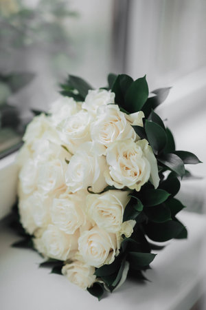 A bouquet of white roses and greenery on a white background. A beautiful photo with details of the wedding. Wedding day. Daylight.の写真素材