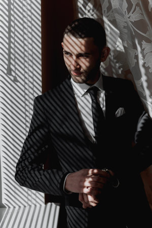 The stylish bridegroom dresses, prepares for the wedding ceremony. The groom's morning. Businessman wears a jacket, male hands closeup, groom getting ready in the morning before wedding ceremonyの写真素材