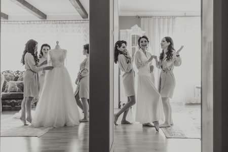 bride's girlfriend prepares the bride for her wedding day. The bride's girlfriend helps secure the bride's wedding dress before the ceremony.の写真素材