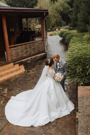 Handsome groom and charming bride together in the park. Portrait. Luxurious dress with a long train. Elegant young groom. Wedding bouquet. luxury weddingの写真素材