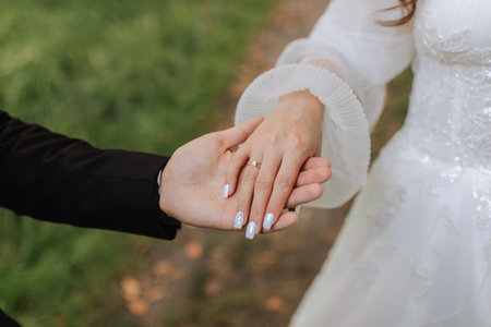 close-up photo, groom holding bride's hand, gold ring on finger, tenderness in photo, blurred...