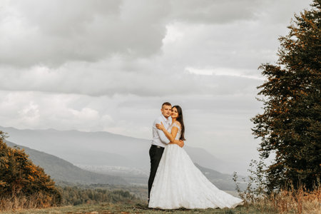 A wedding couple tenderly hugs in the mountains. The groom hugs the bride by the shoulders. A...