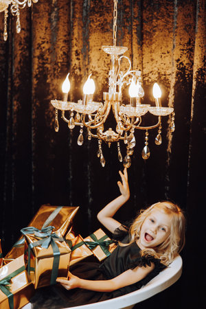 Merry Christmas and Happy Holidays! Cheerful little girl in a bath with Christmas presents in gold wrappers. Children are having fun. Loving family with gifts in the room.の写真素材