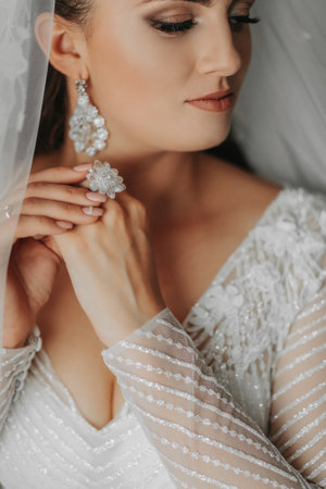 Details. Wedding accessories A brunette bride poses, holding hands beautifully with a crystal wedding ring. Cropped photo. Beautiful hands. Open bust. Crystal jewelryの写真素材