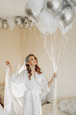 blonde bride with beautiful hair and makeup in her room with balloons in her hands and preparing for the wedding ceremony. Vertical photo.の写真素材