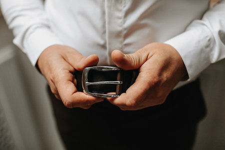 the man holds his black belt in his hands. Close-up photoの写真素材
