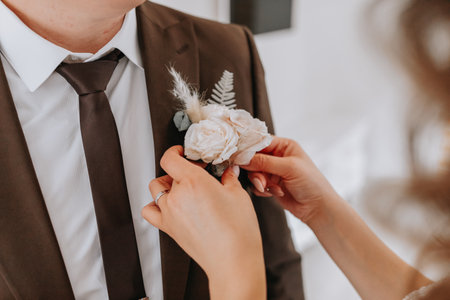 the first meeting of the bride and groom on the wedding day. The bride puts a boutonniere on the groom's jacketの写真素材